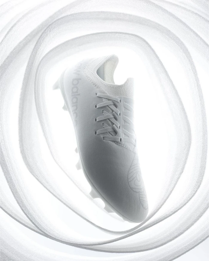 White sports shoe suspended inside a swirling abstract tunnel of white material photographed by Rowan Fee
