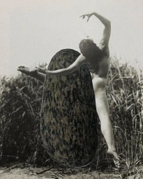 Black and white photographic collage showing a leaping figure partly obscured by a large textured oval form against tall reeds.