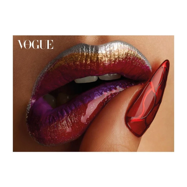 Close-up of metallic makeup on a woman's lips, red fingernail with abstract detail; beauty shot with a fashion magazine logo.