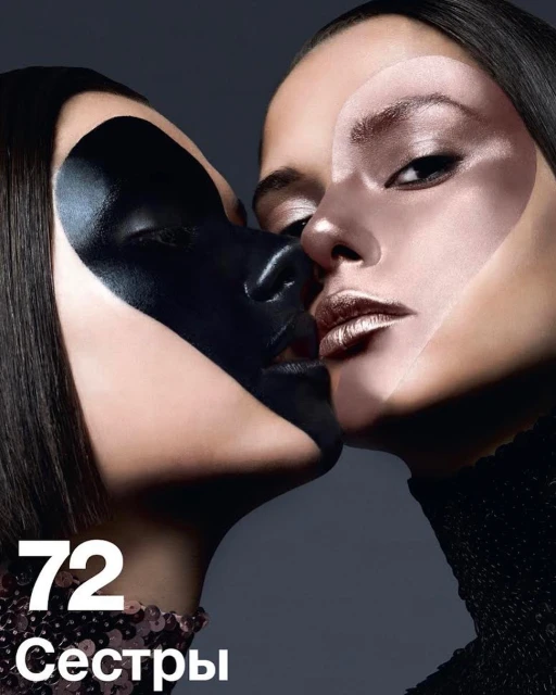 Two women with artistic face makeup in a close-up shot, embracing; one face has bronze tone while the other has black face paint.