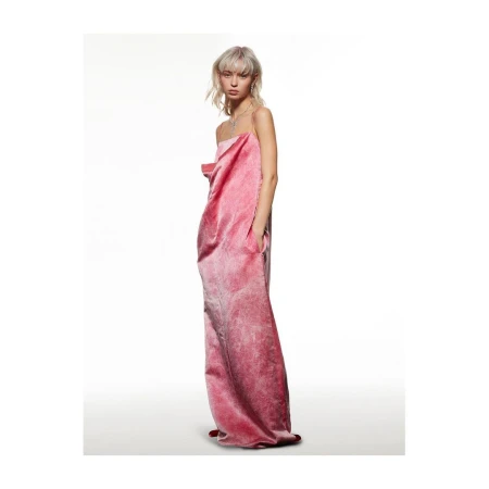 Model with blonde hair wearing a long pink textured gown standing against a plain white studio background.