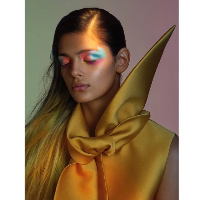Portrait of a woman with creative eye makeup and a yellow satin bow. Beauty shot in soft studio light.