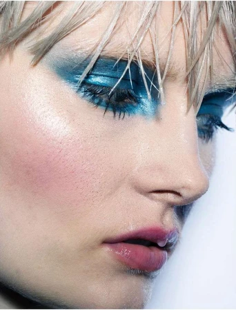 Close-up beauty portrait of a model with vibrant blue eyeshadow and glossy lips photographed by Rui Faria in Paris.