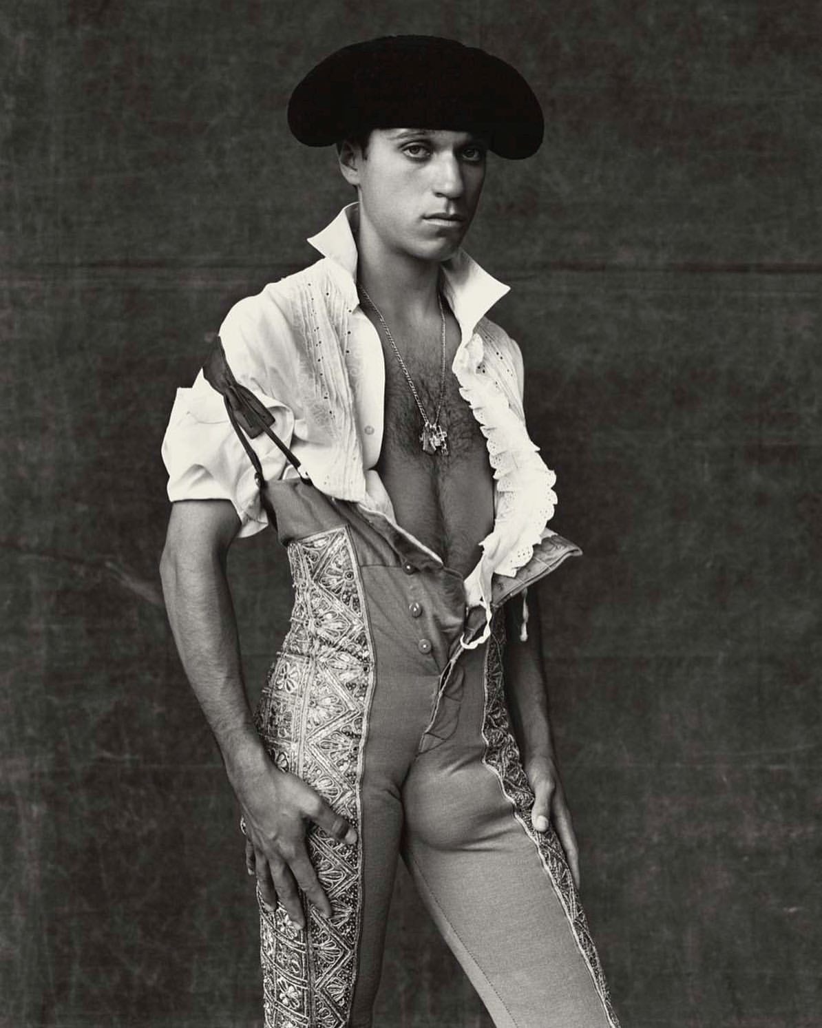Portrait of a man wearing a black hat and traditional Spanish clothing, posing indoors against a dark backdrop with soft lighting.