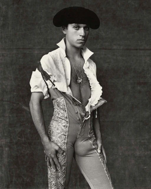 Portrait of a man wearing a black hat and traditional Spanish clothing, posing indoors against a dark backdrop with soft lighting.