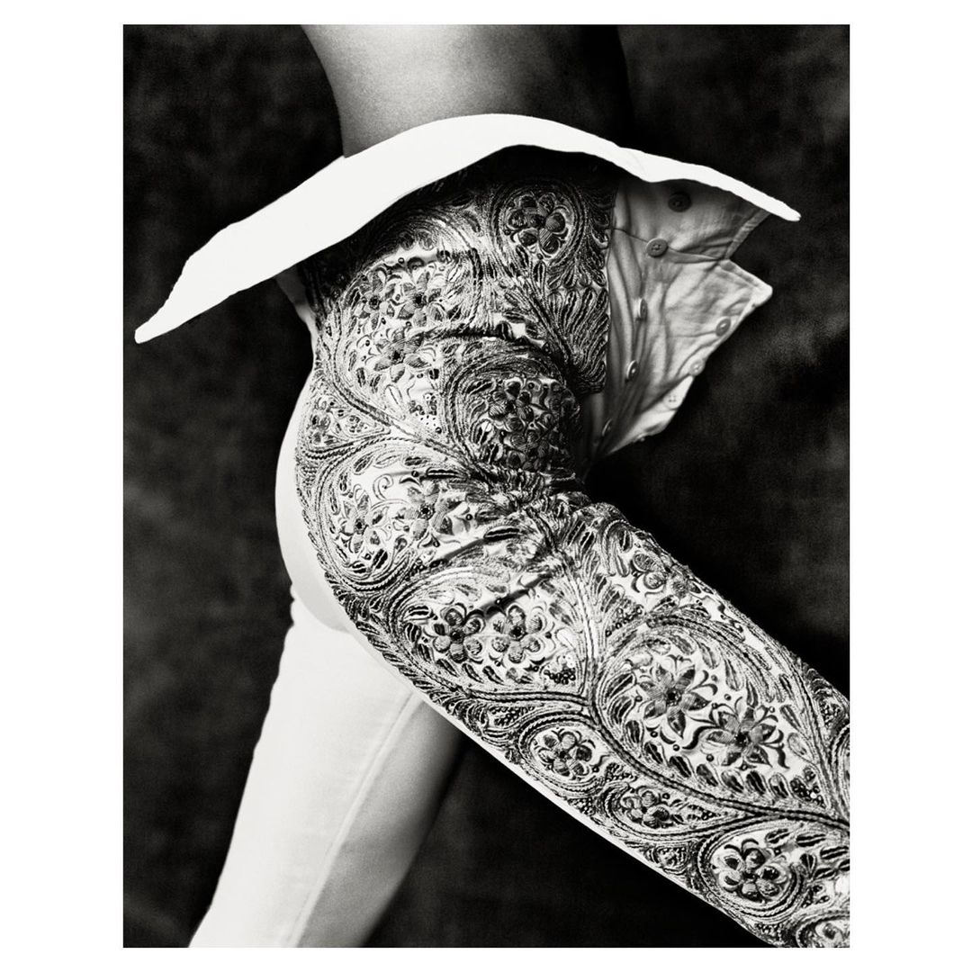 Close-up of a matador in costume featuring a heavily embroidered jacket with silver accents. The image has a monochromatic tone.