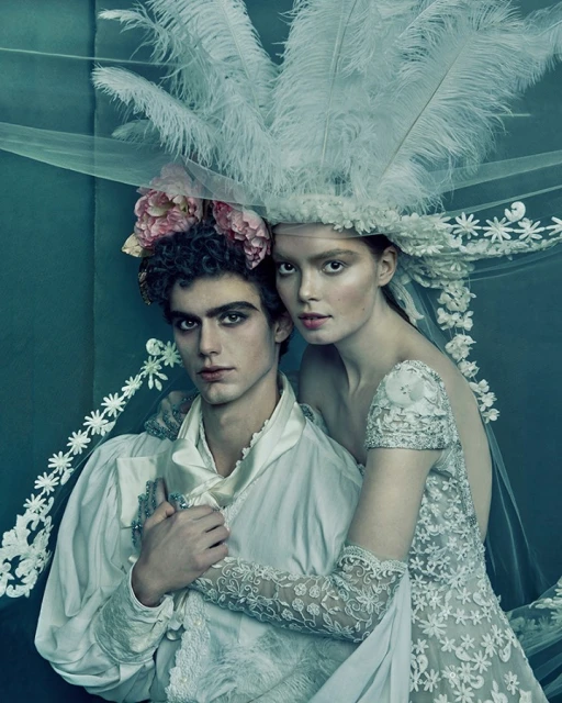 Romantic editorial fashion shot of a couple, the man in a ruffled shirt and the woman in a wedding dress with feathered headpiece.