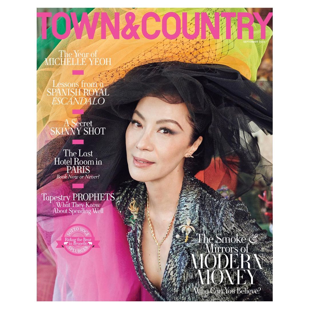 Magazine cover featuring Michelle Yeoh wearing a black veiled headpiece, a sequined jacket, and jewelry, with colorful text overlays.