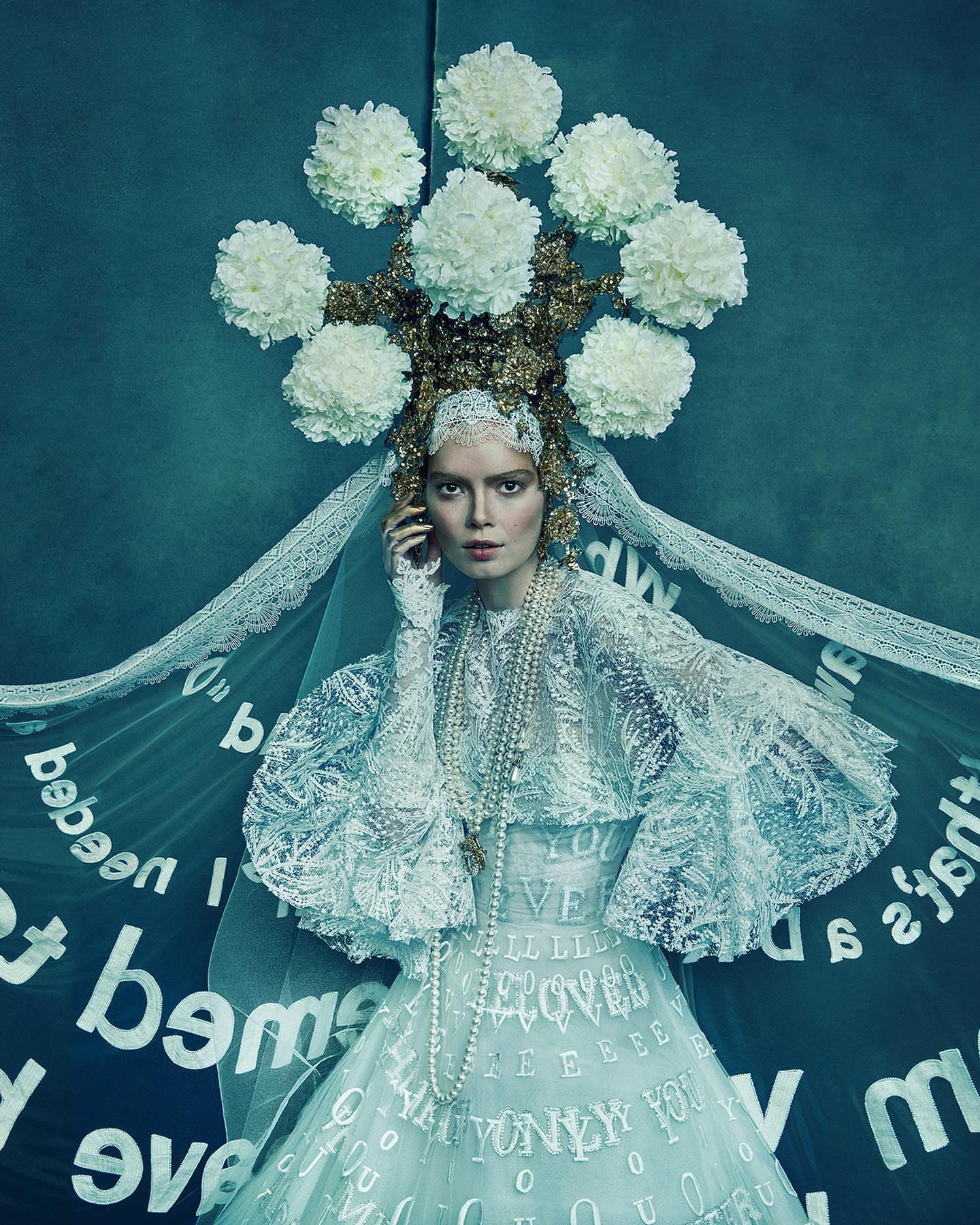 Model in ornate white lace gown with elaborate floral headdress and veil by photographer Ruven Afanador