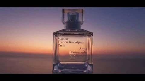 Maison Francis Kurkdjian Paris perfume bottle with a clear glass container against a vibrant orange and purple sunset backdrop.