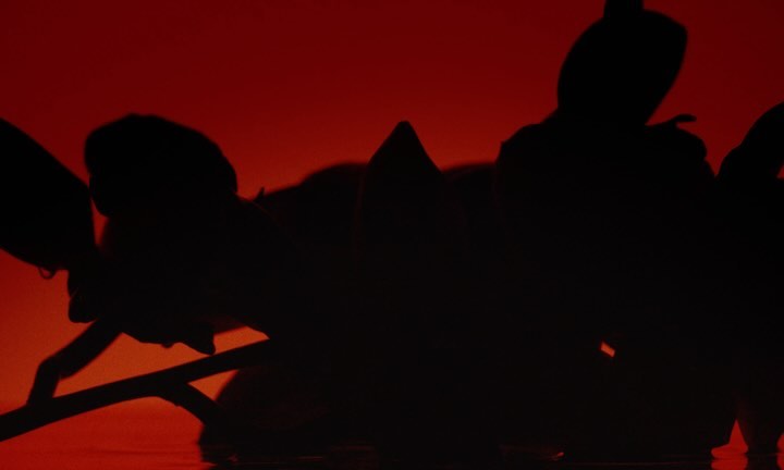 Silhouetted figures engaged in synchronized water sport against a vibrant red backdrop, creating a dynamic and abstract visual.