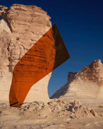 Monumental rock formations stand tall in a desert landscape under a clear blue sky, with an abstract rectangular art piece overlayed.
