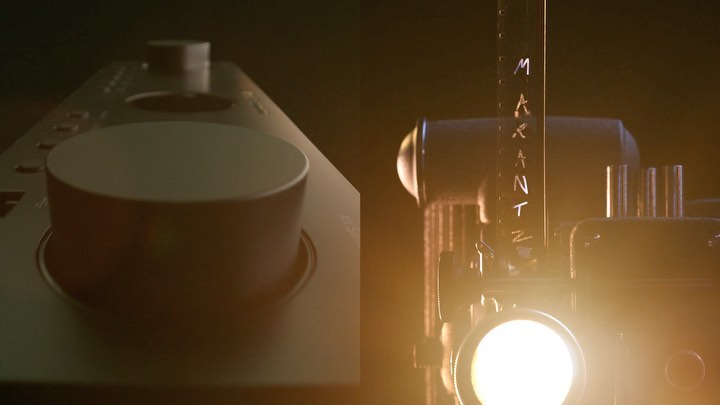 Vintage film projector next to an audio component with a prominent control knob, set against a dark background, illuminated by a warm light.