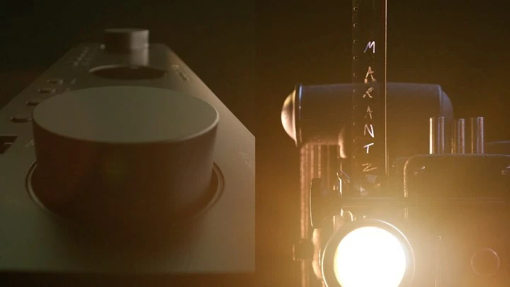Vintage film projector next to an audio component with a prominent control knob, set against a dark background, illuminated by a warm light.