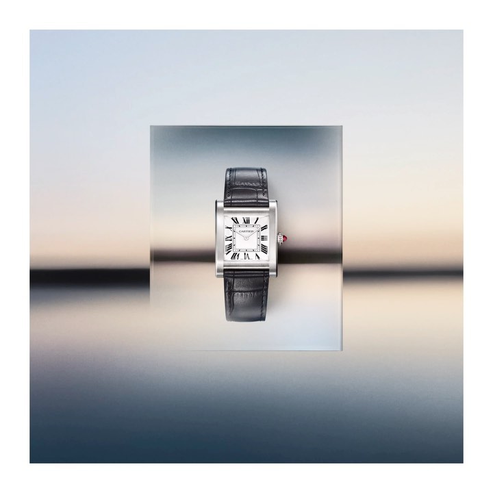 Elevated product shot of a silver and black rectangular wristwatch with a leather band against a gradient blue background.