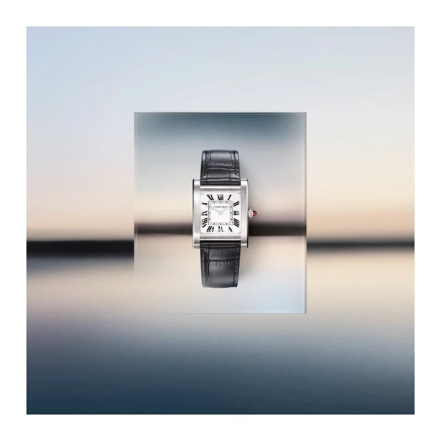 Elevated product shot of a silver and black rectangular wristwatch with a leather band against a gradient blue background.