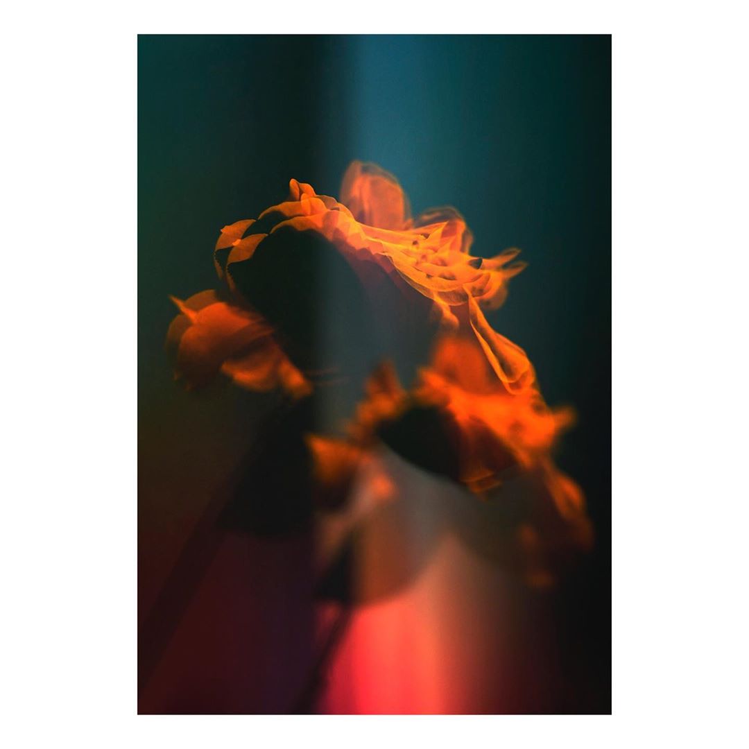 Abstract art piece with blurred orange flame-like shapes against a dark blue background, creating a sense of movement and mystery.