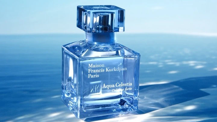 Square glass perfume bottle with blue liquid placed against a water background in a commercial product photograph