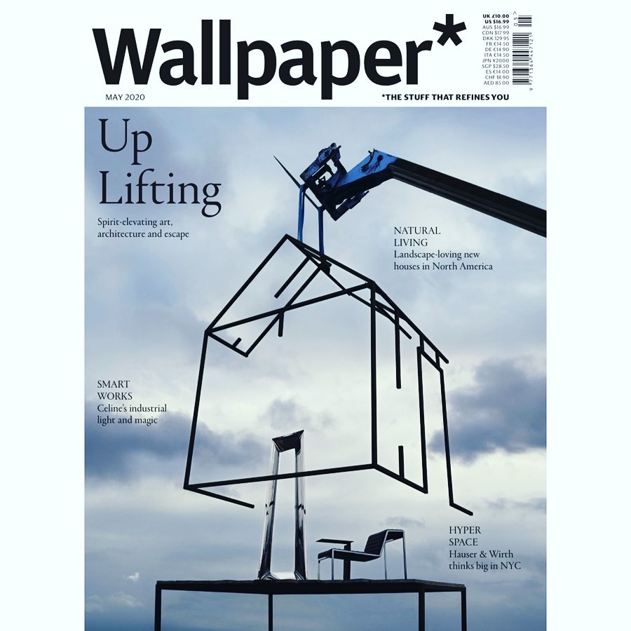 Wallpaper* magazine cover featuring a black line art house frame suspended by a crane, with a chair and pedestal underneath, against a cloudy sky.