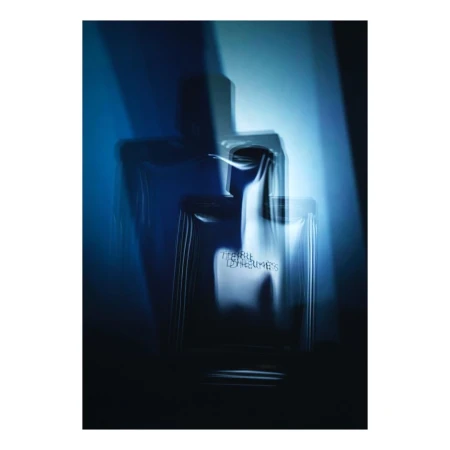 A multiple exposure photograph of a perfume bottle lit with dramatic blue tones and overlapping silhouettes.