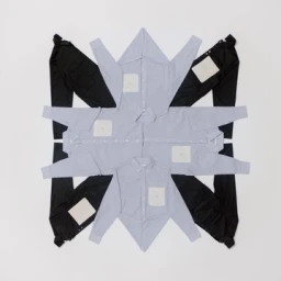 Symmetrical flat lay of light blue button-down shirts and black trousers arranged in a geometric star shape on a white background.