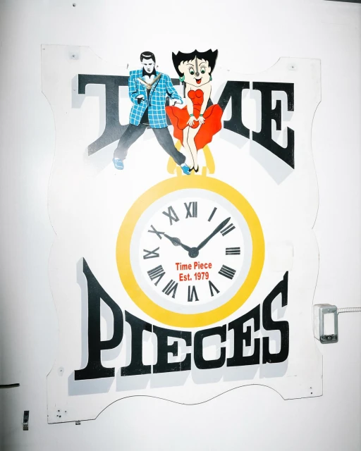 Vintage 'Time Pieces Est. 1979' sign with cartoon figures and a clock, mounted on a white wall, showcasing retro design and functionality.