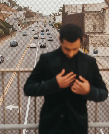 Out-of-focus man in black jacket standing on an overpass overlooking a busy multi-lane highway in New York