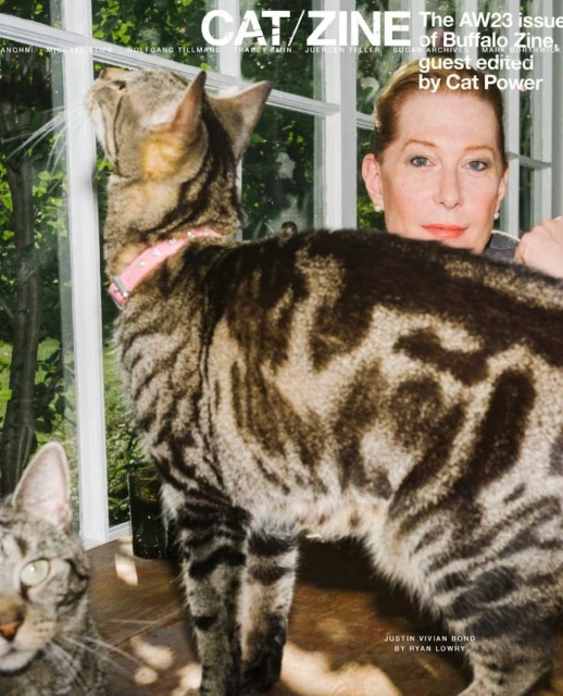 Magazine cover featuring a woman posing with two cats, one wearing a pink collar, with a window and greenery visible in the background.