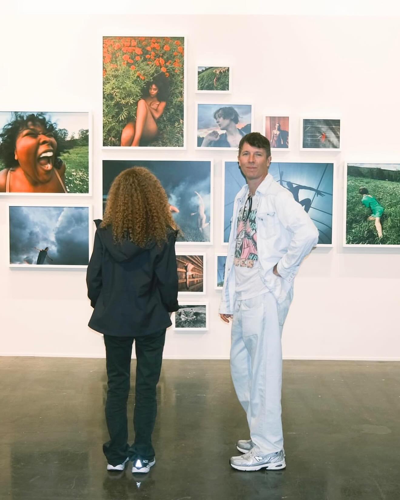 Two people viewing a modern art gallery featuring photography of landscapes and portraits in a well-lit, minimalist gallery setting.