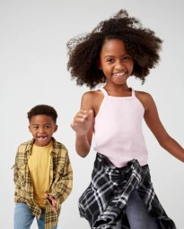 Young girl in a pink tank top and a boy in a yellow shirt against a white seamless background