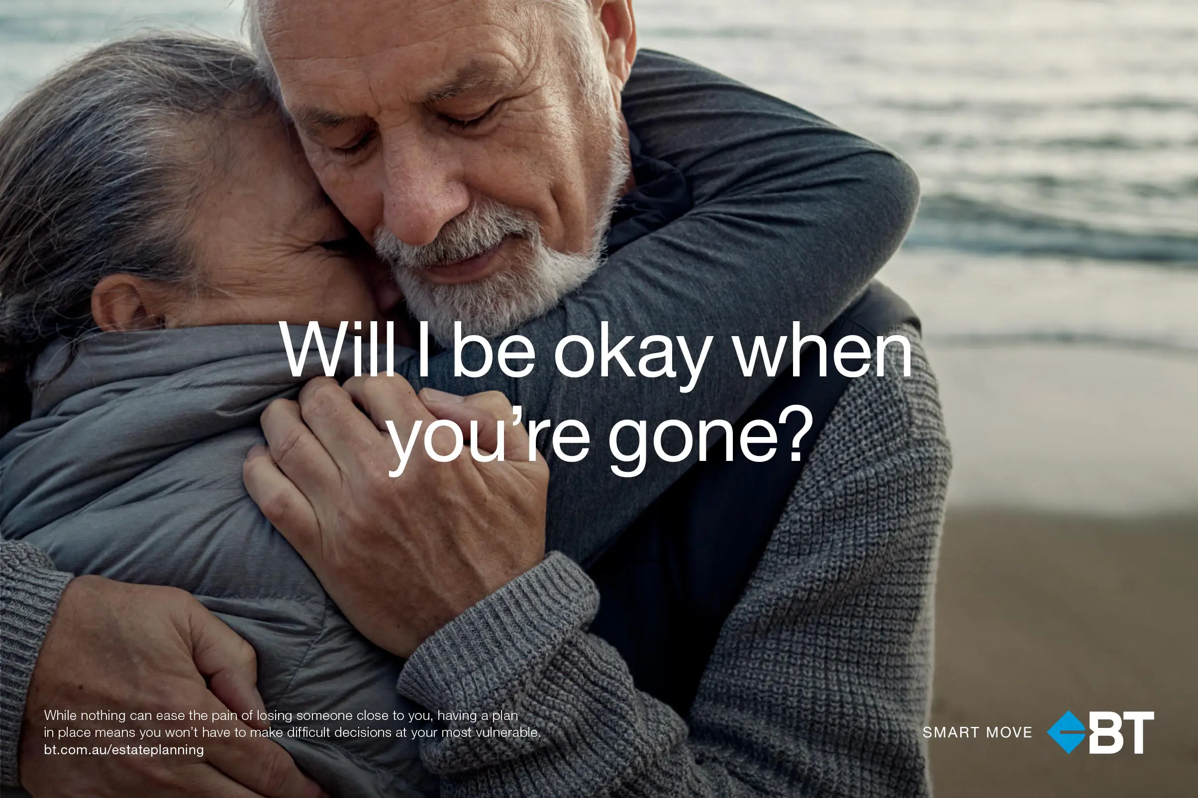 Elderly couple embracing tenderly on a beach with the ocean visible in the background, symbolizing comfort and companionship.