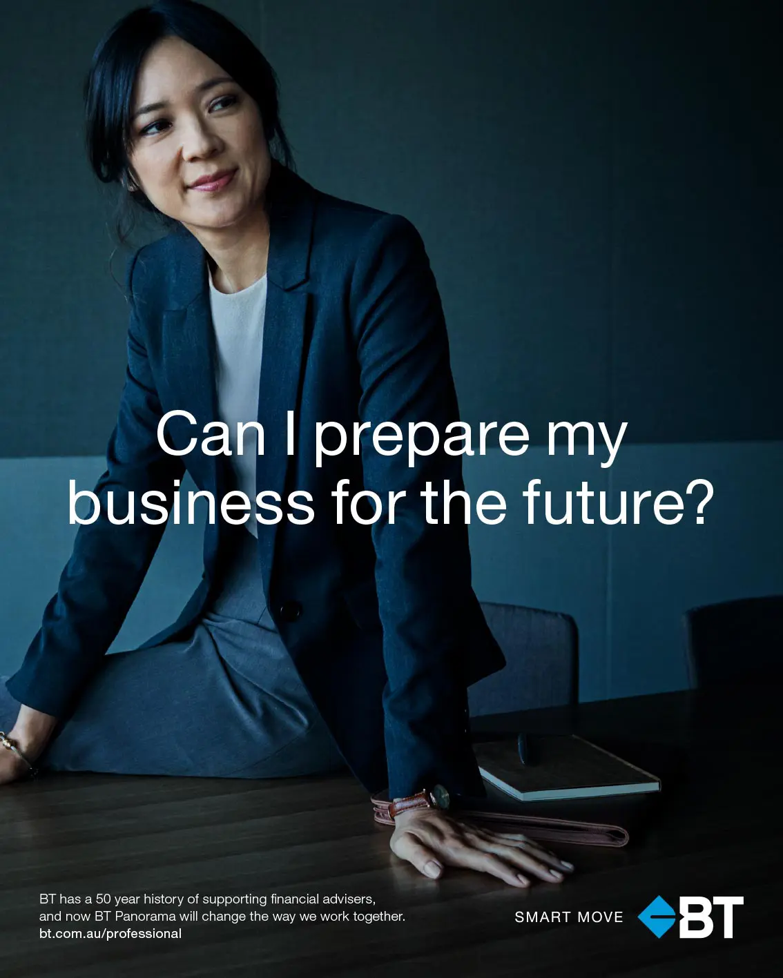 Businesswoman in a navy suit leans on a dark wood conference table in a professional office setting with a modern business advertisement.
