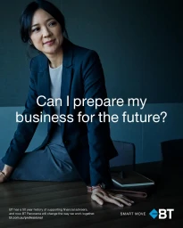 Asian woman in dark blue blazer seated on a wooden table in an office setting for BT Financial Group campaign.