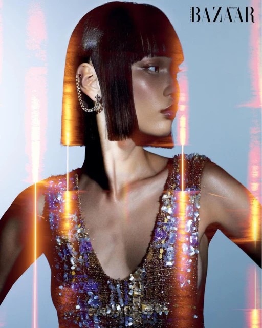 Close-up of a woman with a bob haircut and a sequined dress. She is wearing a silver earring. There is some light flare.