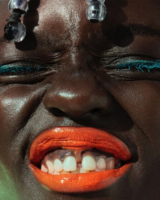 Close-up portrait of an African woman with red lips and beads in her hair, shot in high definition and dramatic lighting conditions.