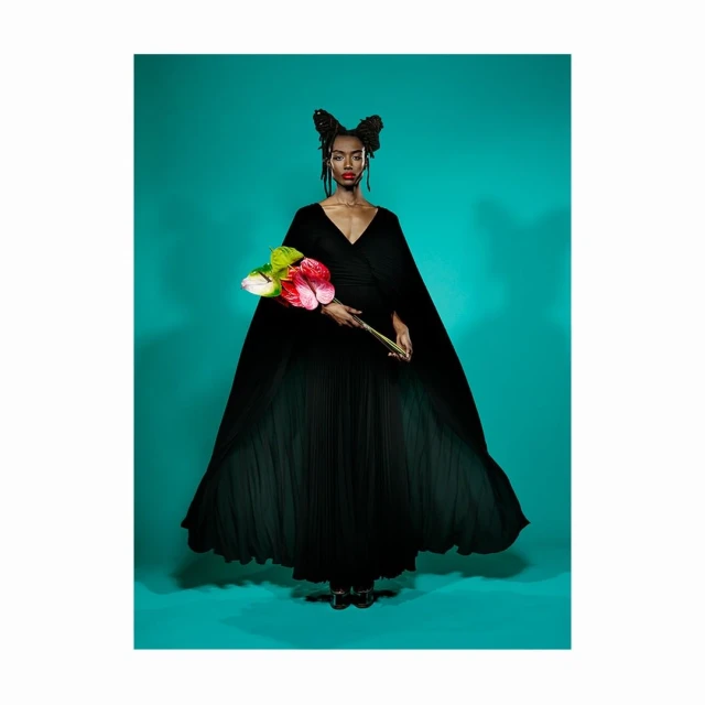 Elegant Black Woman in a Black Gown Holding Anthurium Flowers against a Turquoise Background in a Fashion Editorial Photo Shoot.