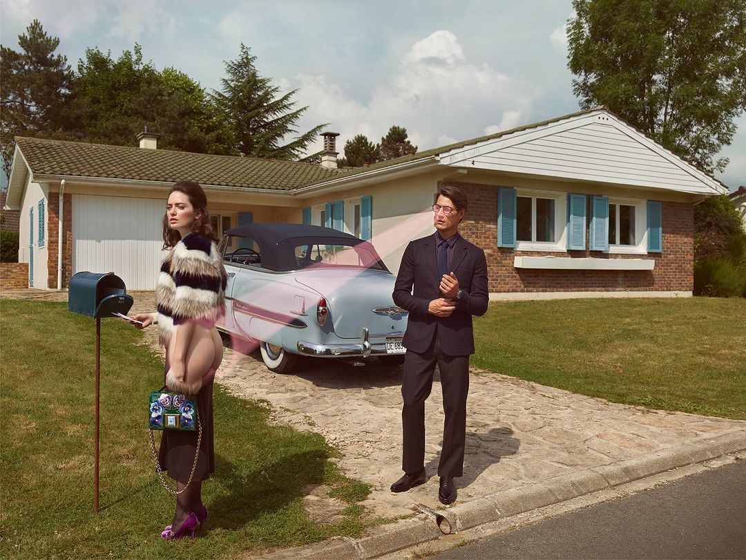 Fashion editorial shot of a stylish couple in front of a house with a vintage car, the woman wearing a fur coat, the man in a suit.