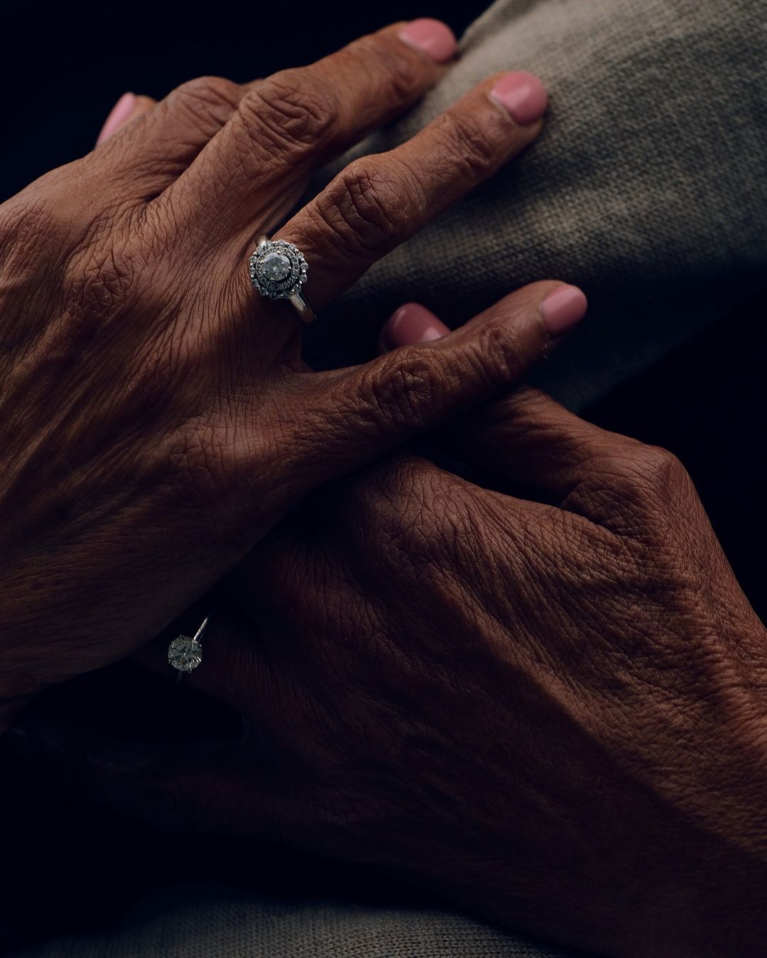 Close-up of a pair of hands adorned with diamond rings, capturing the details of the skin texture and jewelry in soft lighting.