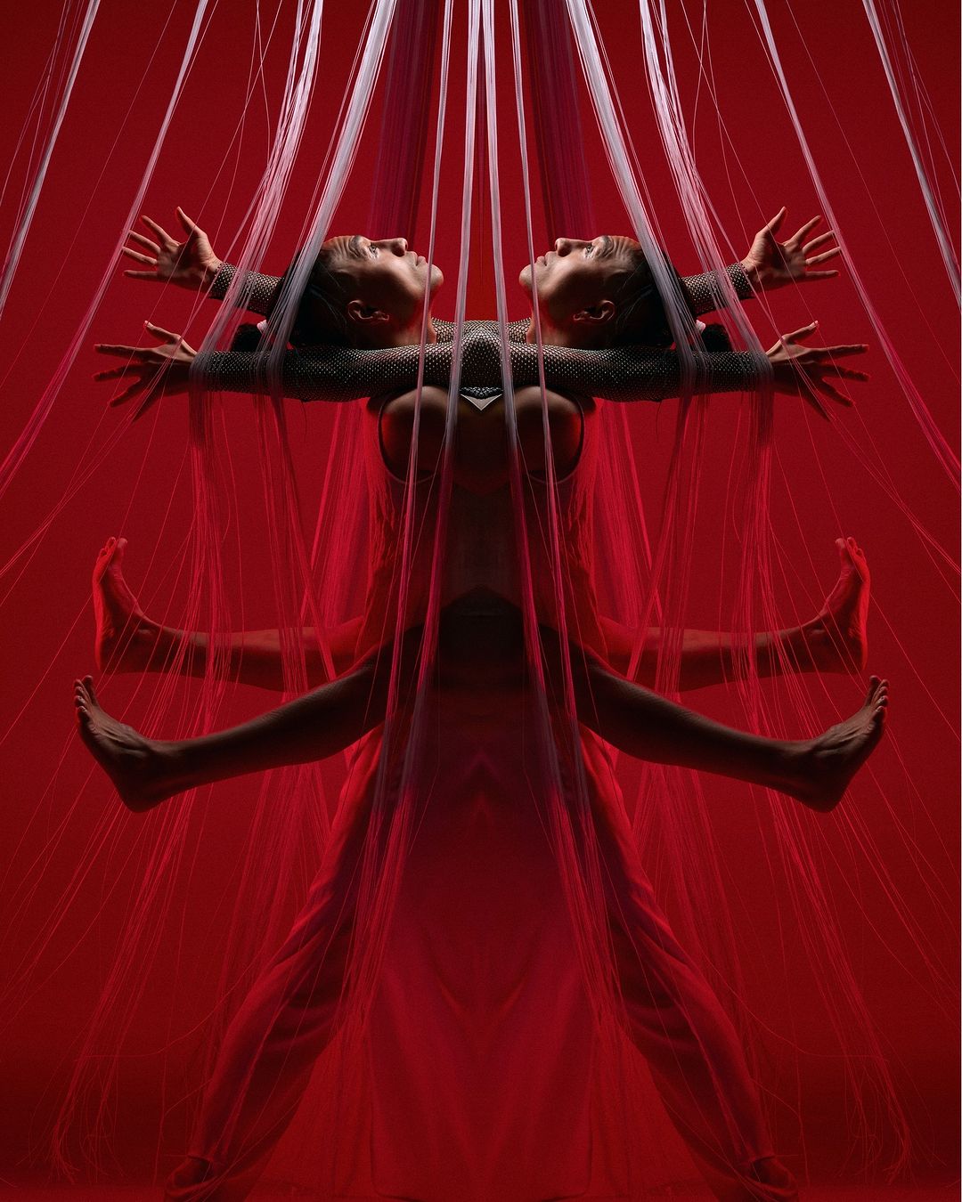 Surreal portrait featuring an adult female in a pose with transparent strings, set against a vivid red backdrop in a photo studio environment.
