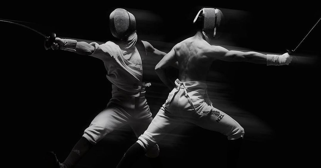 Two fencers in action, wearing protective gear and holding foils, engaged in a match with a black background, motion blur effect.
