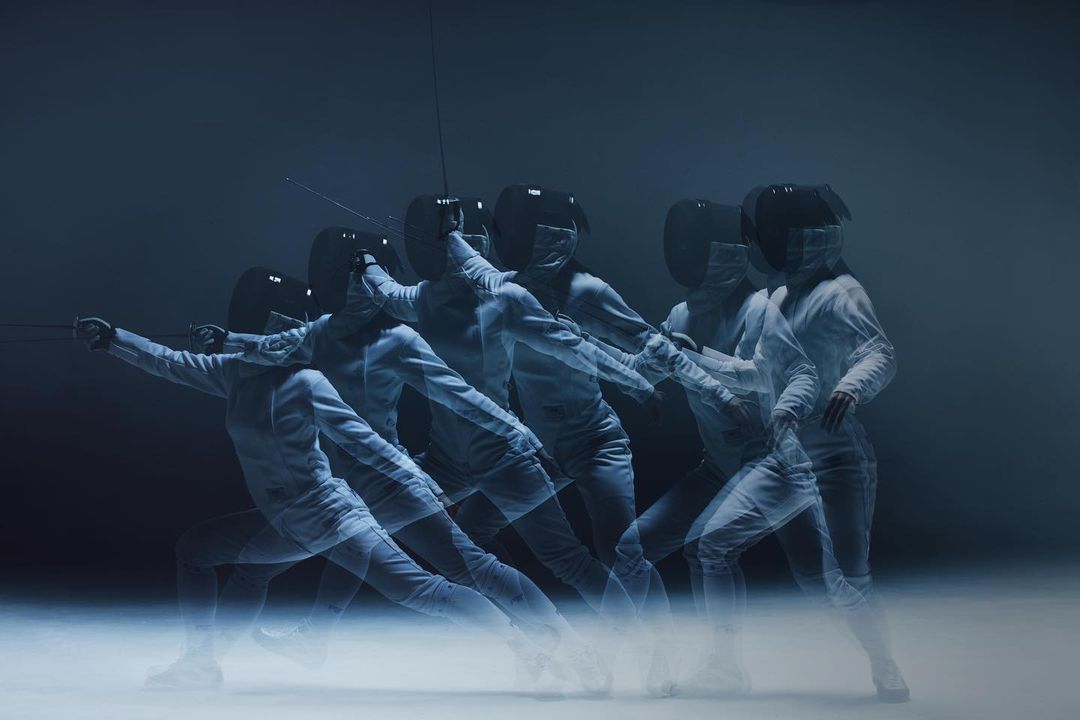 Multiple exposures of a fencer in white fencing gear and black mask performing a fencing move against a dark background.