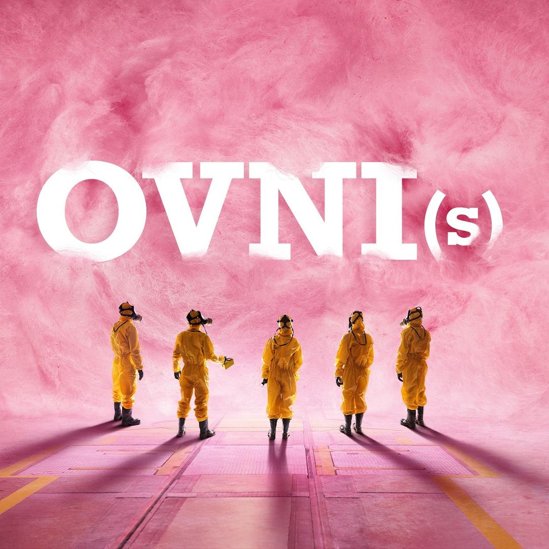 Five people in yellow hazmat suits and masks standing on a pink tiled surface with a pink puffy cloud background and large white text.