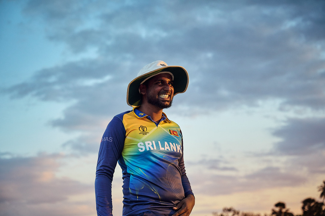 Man smiles wearing Sri Lanka cricket jersey, sun hat, and sky background, capturing sport, fashion, and outdoor enjoyment.