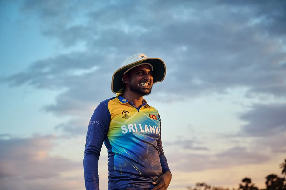 Man smiles wearing Sri Lanka cricket jersey, sun hat, and sky background, capturing sport, fashion, and outdoor enjoyment.