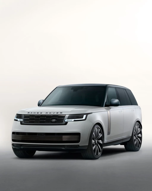 Luxury Range Rover SUV in a studio shot. Car features a light grey exterior, black roof, and large black wheels against soft lighting.
