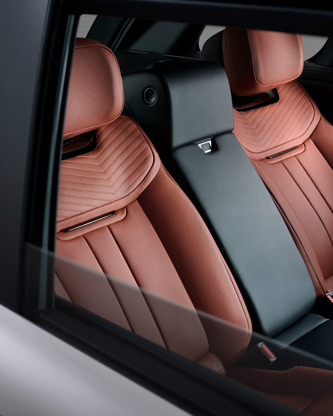 Automotive interior shot showcases plush, quilted leather seats with black accents inside a vehicle, seen through a car window.