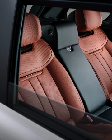 Automotive interior shot showcases plush, quilted leather seats with black accents inside a vehicle, seen through a car window.