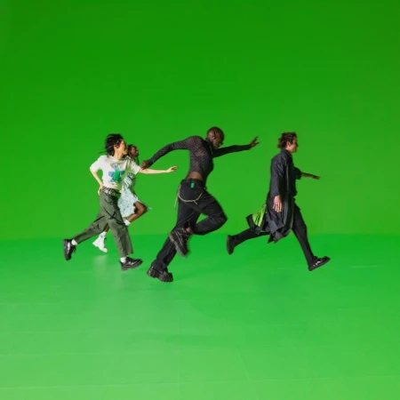 Four people in athletic wear running at eye level against a bright green backdrop, motion blur suggests speed and energy.