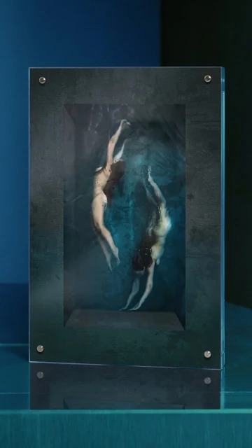 Two adult females appear to float in an abstract, surreal underwater scene depicted inside a dark-framed display object.
