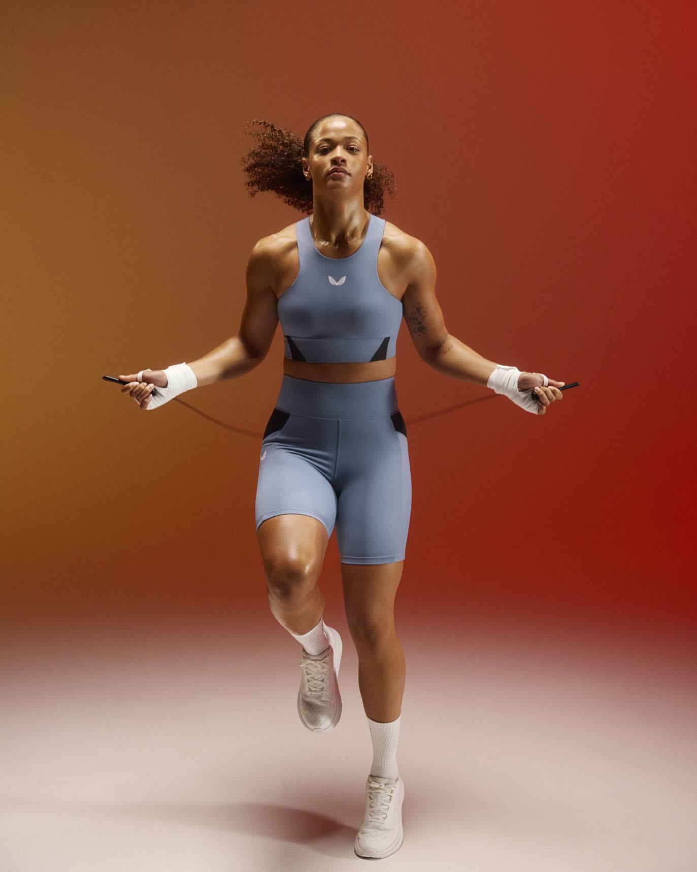 Athletic woman in sportswear jumps rope against a gradient background. The image captures a dynamic moment of fitness and athleticism.